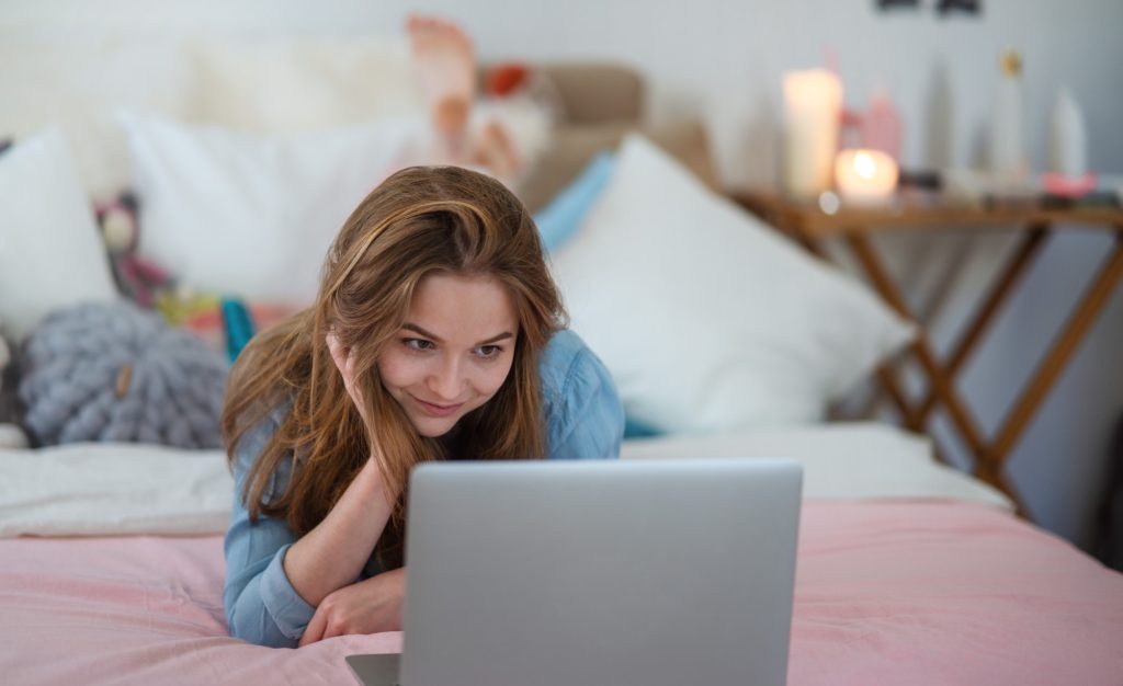 Beautiful happy young girl with laptop sitting and smiling, online dating concept