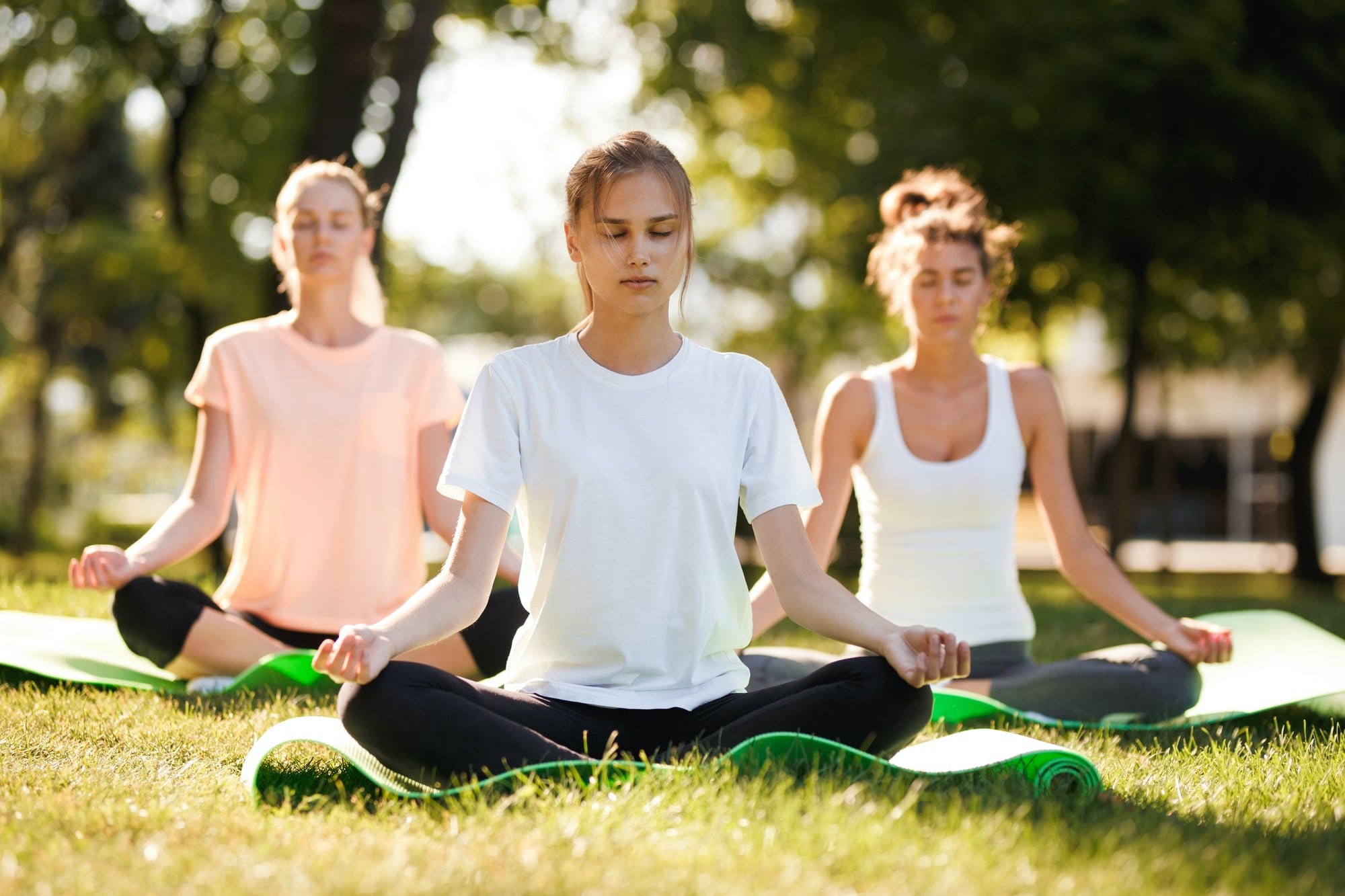 Group of young women practicing yoga, morning meditation in nature at the park