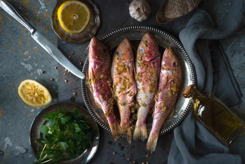 Plate of fried small fish red mullet and olive oil