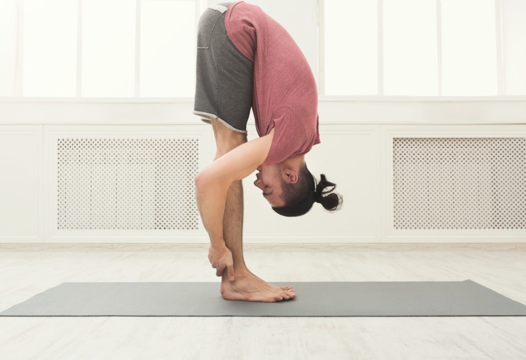 Sporty man doing Standing Forward Bend