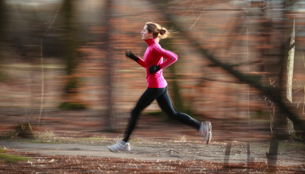 Young woman running outdoors in a city park on a cold fall/winte