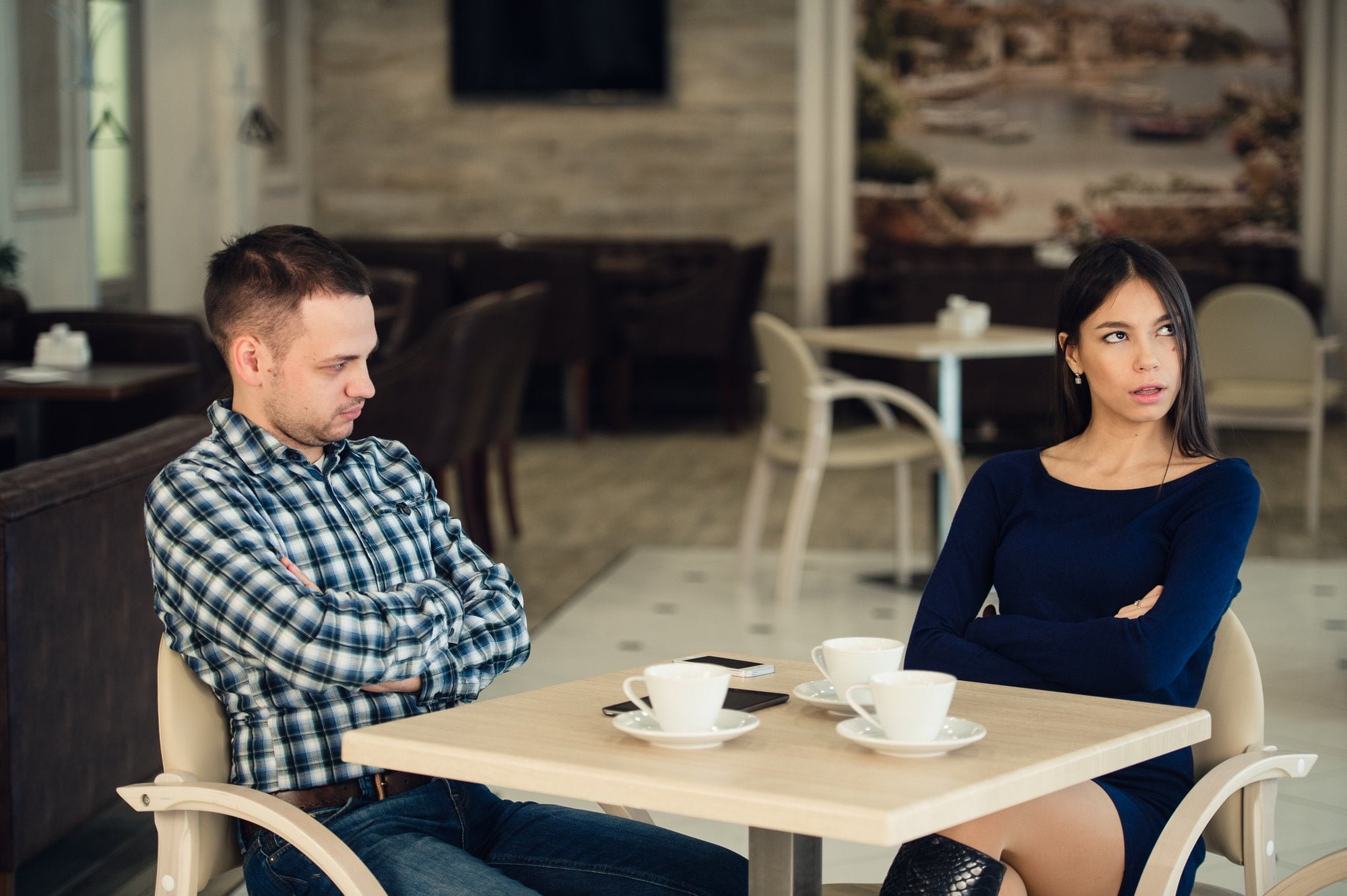 Young unhappy married couple having serious quarrel at cafe