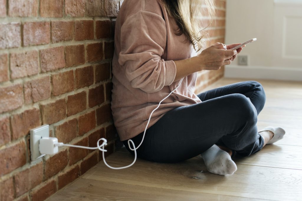 Young woman using a smartphone as it is being charged