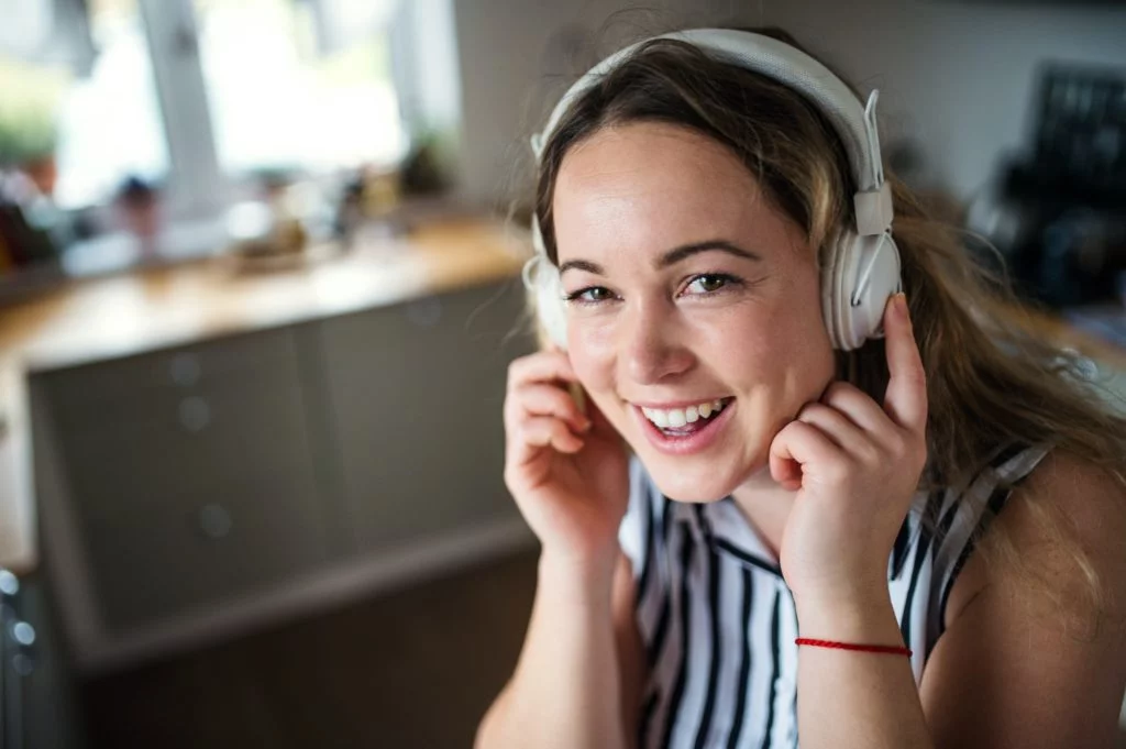Young woman with headphones relaxing indoors at home, listening to music
