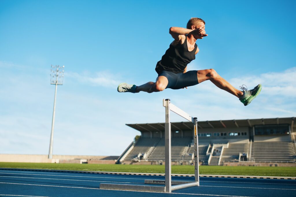 Professional sprinter jumping over a hurdle