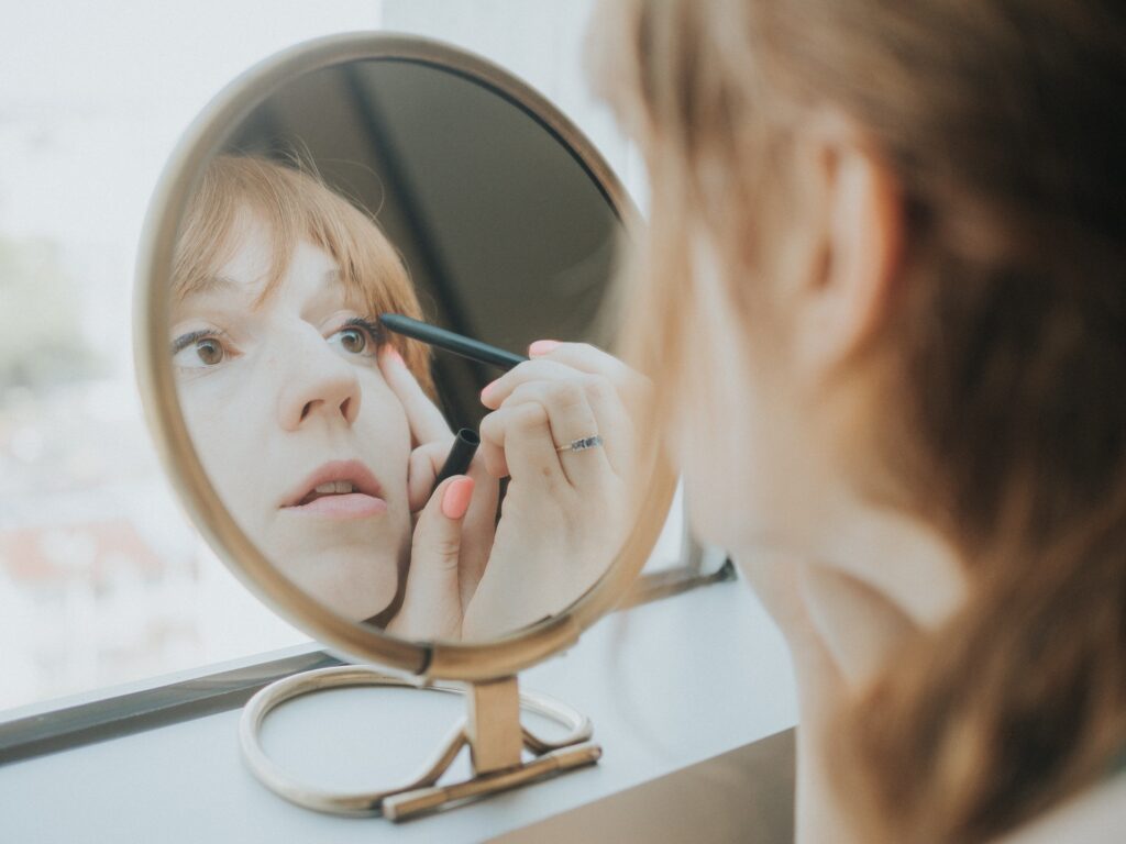 Woman Putting on Makeup in the Mirror