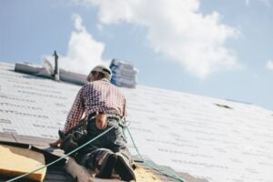 Roofer adding shingles to the roof of a house